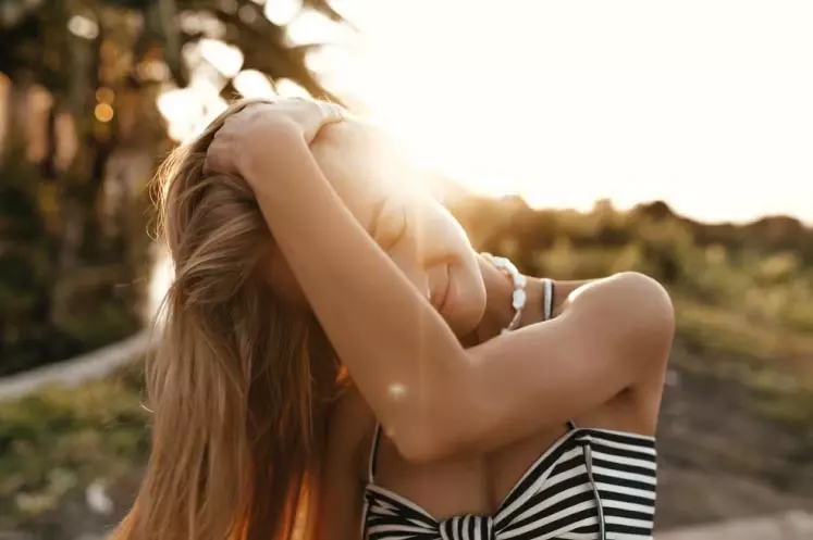 Plan rapproché poitrine sur une blonde penchant la tete sur la gauche, cheveux cachant le visage