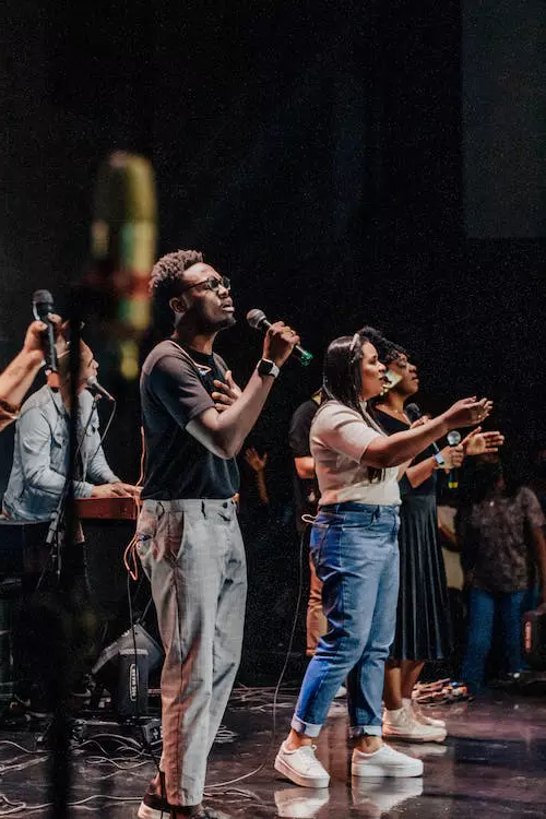 Groupe de personnes chantant ensemble, les bras levés en signe d'unité et de joie.